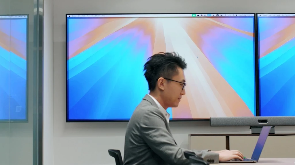 Person presenting to dual wall displays after connecting with AirMedia