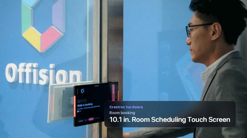 Person approaching a glass meeting room with a Crestron panel showing occupied status in red