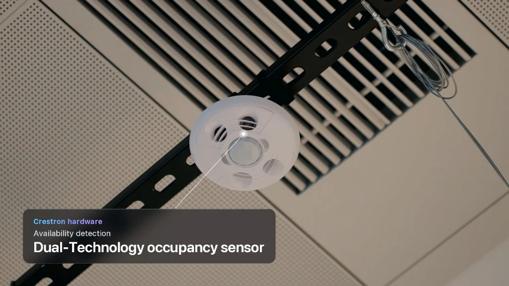 Circular Crestron dual-technology occupancy sensor on a ceiling track